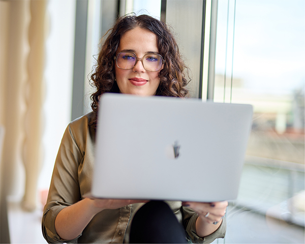 Inhaberin am Laptop auf Fensterbank sitzend
